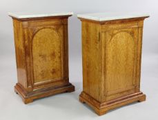 A pair of Victorian marble top satinwood cabinets, each with a single arched panelled door