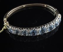 A gold, diamond and graduated aquamarine hinged bracelet, set with round cut stones.