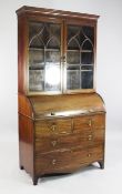 An early 19th century mahogany cylinder bureau, with two astragal glazed doors above revolving