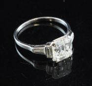 A platinum and emerald cut single stone diamond ring, with baguette cut diamond set shoulders, the