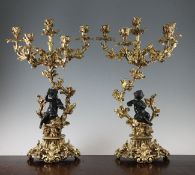 A pair of French bronze and ormolu five branch candelabra, one modelled with a seated boy, the