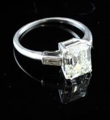 A platinum and single stone emerald cut diamond ring, with baguette cut diamond set shoulders, the
