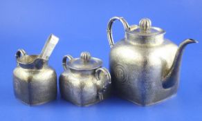 A 19th century Chinese silver three piece tea set and sugar tongs by Tu Mao Xing of Jiujiang, with