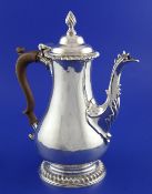 An early George III silver coffee pot, of baluster form, with gadrooned borders, scroll wood handle