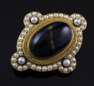 A Victorian gold, tiger`s eye and pearl set oval brooch, the central stone with rope twist border,