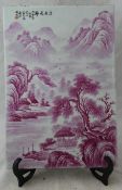 A Chinese puce enamelled porcelain plaque, painted with figures in a mountainous river landscape,