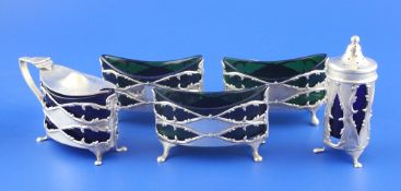 A matched Edwardian five piece silver condiment set, comprising three salts, a mustard and