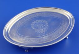 A George III silver oval teapot stand, with engraved foliate band and monogram, on four tapered