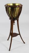 An Edwardian stained beech circular jardiniere stand, with lion mask and beaded chains, on outswept