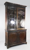A George III style mahogany bookcase, fitted with a pair of astragal glazed doors over two cupboard