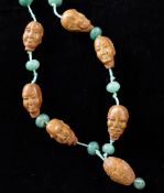 A Chinese peach stone and green stone bead necklace, ten peach stones carved as the heads of