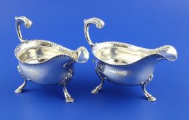 A pair of George III silver sauceboats, with pinched borders and flying scroll handles, on three