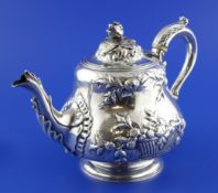 A Victorian silver teapot, of squat pear form, with engraved armorial and embossed with baskets of