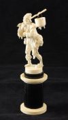 A 19th century carved Dieppe ivory figure of a beggar, with his arm in a sling, on a circular ebony