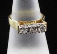 An 18ct gold three stone diamond ring, with raised setting, the total diamond weight approximately