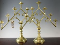 A pair of Gothic brass candelabra, each mounted with seven sconces with circular drip pans, 21in.