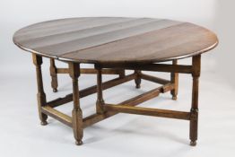 A large oak oval gateleg dining table, on tapering column supports, united by stretchers, extended