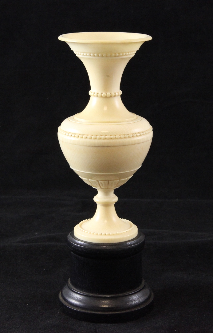 A 19th century carved and turned Dieppe ivory vase, with trumpet neck and circular base, on an