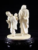 A Japanese ivory okimono of a man trying to amuse a crying baby on a girl`s back, Meiji period, the