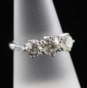 An 18ct white gold and three stone diamond ring, with diamond set shoulders and a total approximate