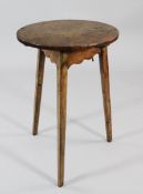 A 19th century elm and pine country circular cricket table, on tapering chamfered legs, the