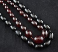 Two single strand graduated simulated amber bead necklaces, one red, one black, 30in & 35in.