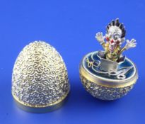 A 1980`s textured silver gilt and enamel novelty surprise egg by Stuart Devlin, opening to reveal a