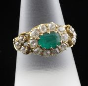 A Victorian style emerald and diamond cluster ring, with central oval motif and ornate carved