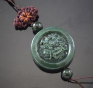 A Chinese spinach green jade disc pendant, carved in relief to one side with a dragon`s head and
