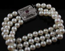 A triple strand cultured pearl bracelet with 14ct white, ruby and diamond set rectangular clasp, 7.