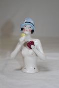 A 1920`s Continental porcelain pin cushion doll, with head and torso, holding a make-up compact,