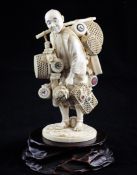 A Japanese ivory figure of a street seller, Meiji period, carrying baskets, brushes and a samurai