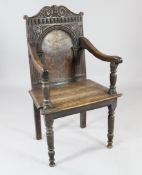 A 17th century carved oak elbow chair, the arched panel back with scrolling inlay and central