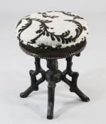 An early 20th century Black Forest carved circular revolving piano stool, with upholstered pad seat