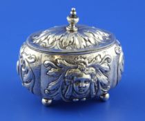A 19th century German? silver oval sugar box and cover, embossed with masks and scrolls, on four