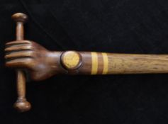 An unusual palm wood walking cane, the handle carved as a hand wearing a wrist watch gripping a