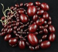 Two single strand graduated simulated red amber bead necklaces, (one in need of re-stringing),