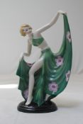 An Art Deco porcelain figure of a dancer, by Fasold & Stauch, holding the drapes of her green and