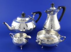 An Edwardian Art Nouveau four piece planished silver tea set by Charles Edwards, of squat circular