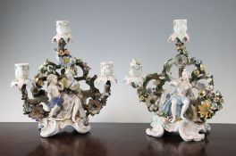 A pair of German porcelain figural three light candelabra, late 19th century, each modelled with a