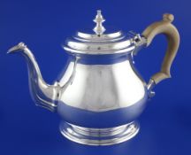 A 1960`s George I style silver teapot, of squat baluster form, with fluted spout and turned wooded