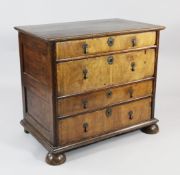 An 18th century walnut and oak chest of four long drawers, on bun feet, W.3ft .5in.