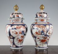 A pair of Arita baluster vases and cover, c.1680-1720, each painted with reserves of pavilions in