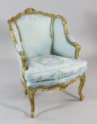 A Louis XV style carved giltwood armchair, upholstered in blue floral damask upholstery, decorated