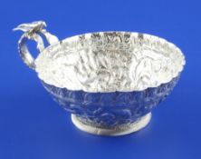 A 19th century Persian silver cup, heavily embossed with serpents, deer and lion, the single handle