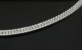 A 14ct white gold and diamond line bracelet, set with sixty four round cut diamonds, 7in.