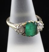 A gold, three stone emerald and diamond ring, with carved scroll setting, the central emerald