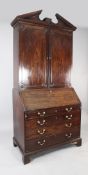 A George III mahogany bureau bookcase, with broken arch pediment over two panelled doors enclosing