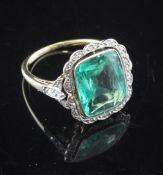 A gold, emerald and diamond cluster ring, the cushion cut emerald weighing 3.87ct, with diamond set