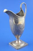 A George III silver helmet shaped cream jug, with reeded handle and engraved with foliate swags and